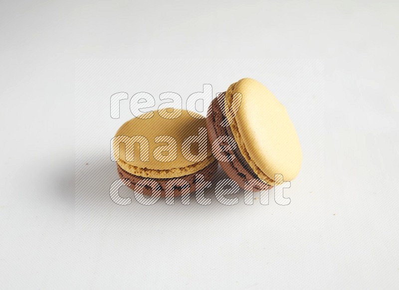 45º Shot of two Yellow and Brown Chai Latte macarons on white background