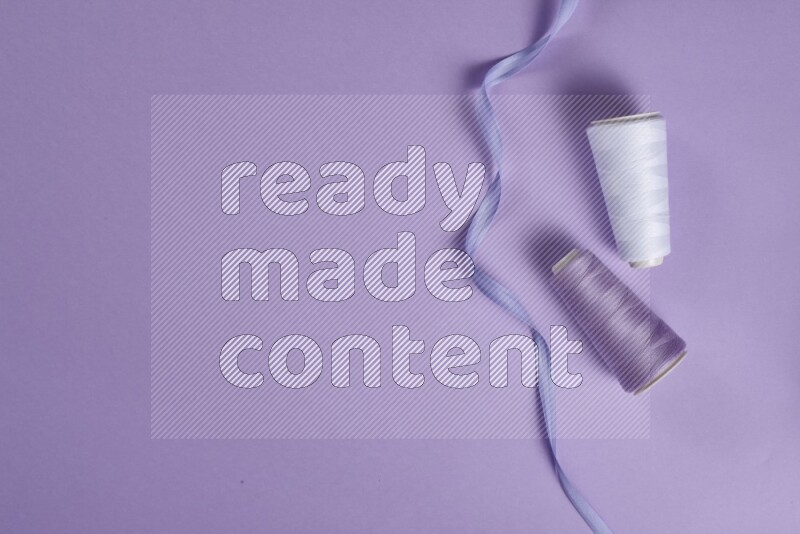 مجموعة من أدوات الخياطة والتفصيل بيضاء وأرجوانية اللون على خلفية أرجوانية