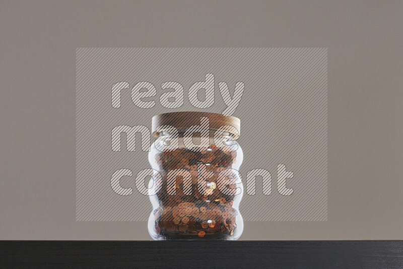 Sequins in a glass jar on black background