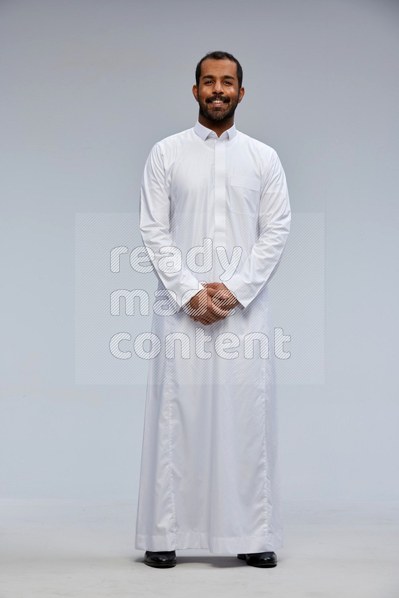 Saudi man Wearing Thob standing interacting with the camera on Gray background