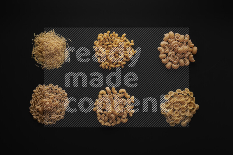 Different pasta types in bunches on black background