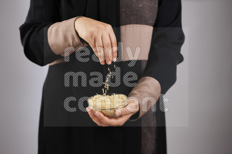 Woman in abaya holding different kinds of legumes in different positions