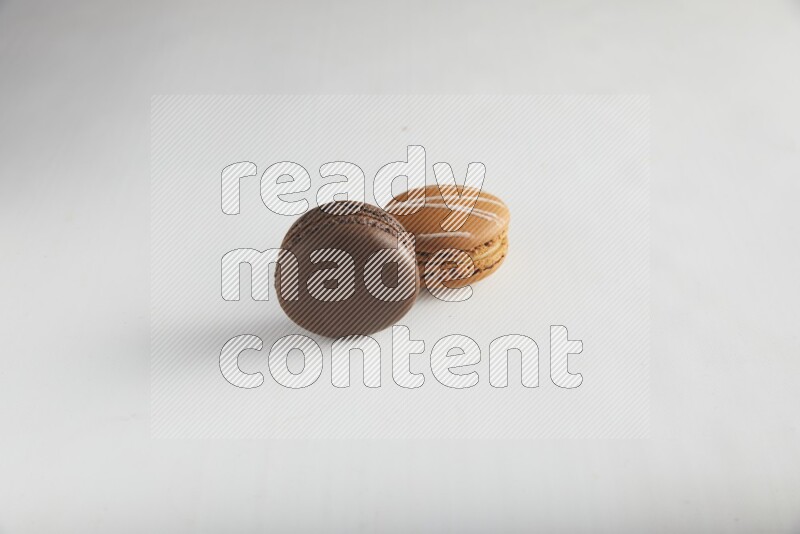 45º Shot of of two assorted Brown Irish Cream, and Brown Dark Chocolate macarons on white background