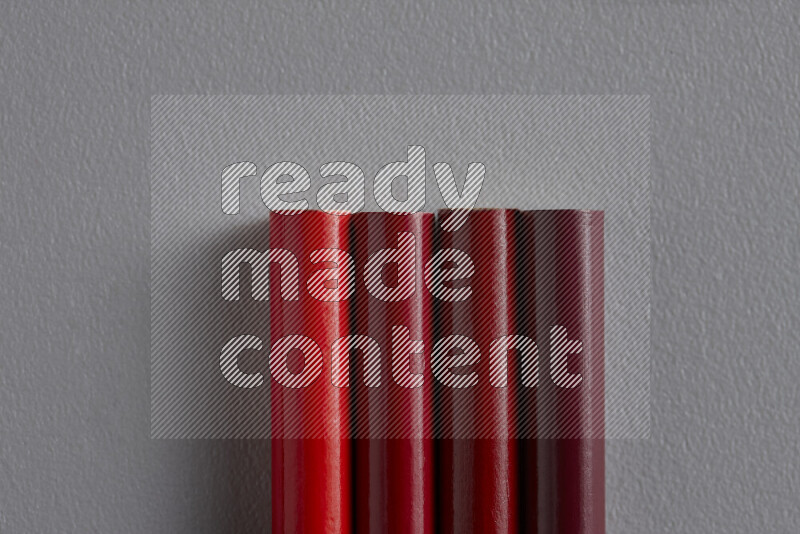 A collection of sharpened colored pencils arranged showcasing a gradient of red hues on grey background