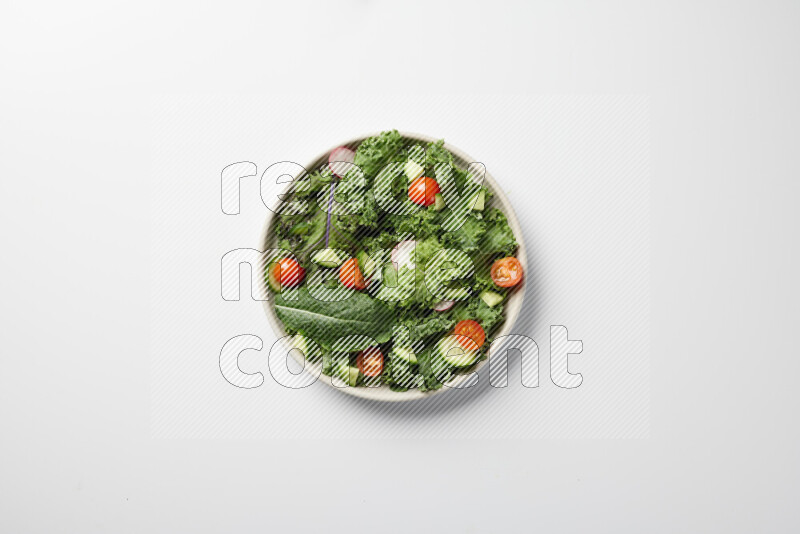 A bowl of fresh vegetables salad with kale leaves, cherry tomatoes, sliced radishes and sliced cucumber on a white background