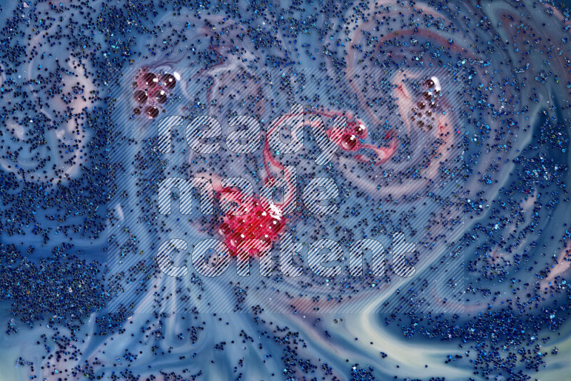 A close-up of sparkling blue glitter scattered on swirling blue and red background