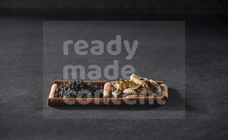 2 squares of cinnamon sticks full of black peppers and turmeric fingers on black flooring