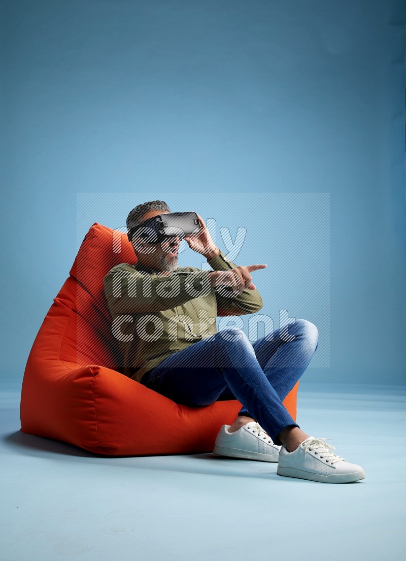 A man sitting on an orange beanbag and gaming with VR