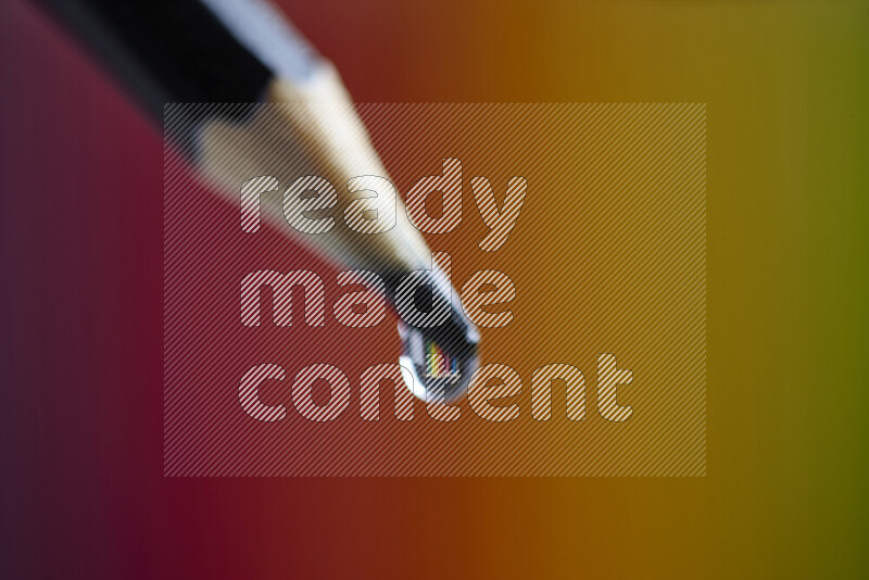 تلتقط الصورة عن قرب قطرة ماء متوازنة على طرف قلم رصاص حاد مع خلفية ملونة ضبابية