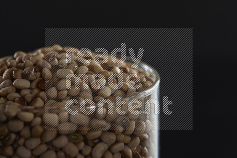 Black-eyed peas in a glass jar on black background