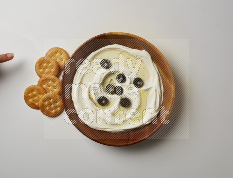 Lebnah garnished with sliced olives in a wooden plate on a white background