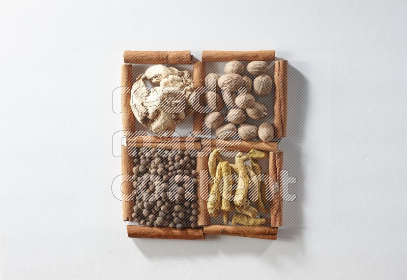 4 squares of cinnamon sticks full of nutmegs, dried ginger, turmeric fingers and allspice on white flooring