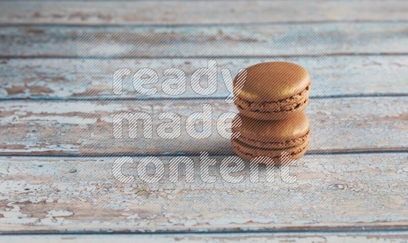 45º Shot of two Brown Coffee macarons on light blue wooden background
