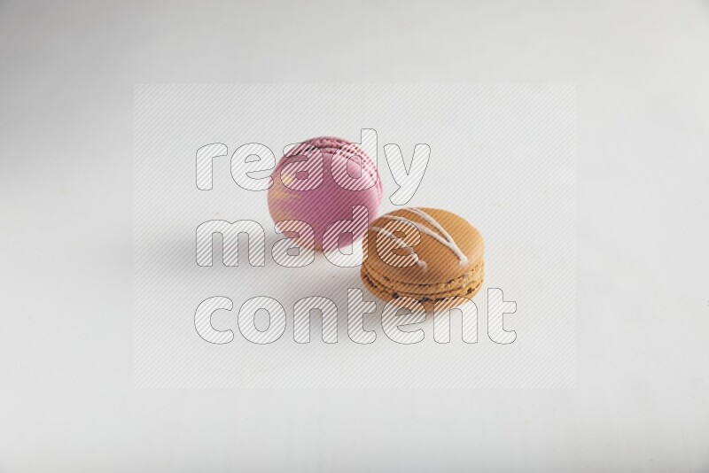 45º Shot of of two assorted Brown Irish Cream, and Purple Strawberry macarons on white background