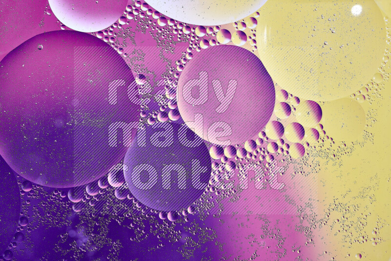 Close-ups of abstract oil bubbles on water surface in shades of yellow, purple and pink