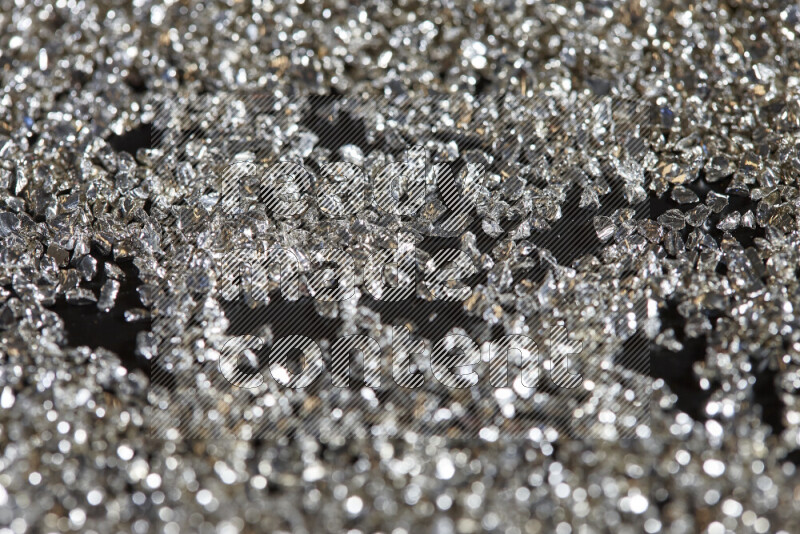 Silver shimmering fragments of glass scattered on a black background
