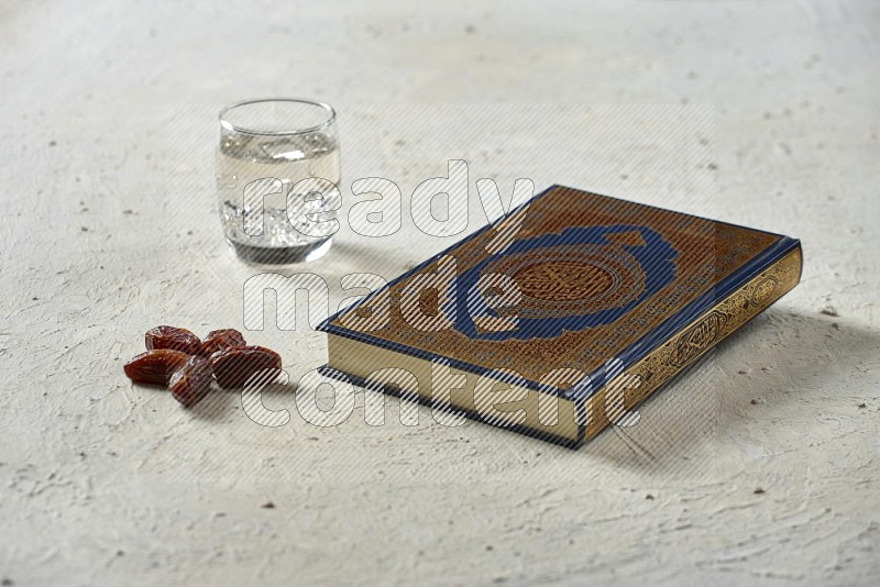 Quran with dates, prayer beads and different drinks all placed on textured white background