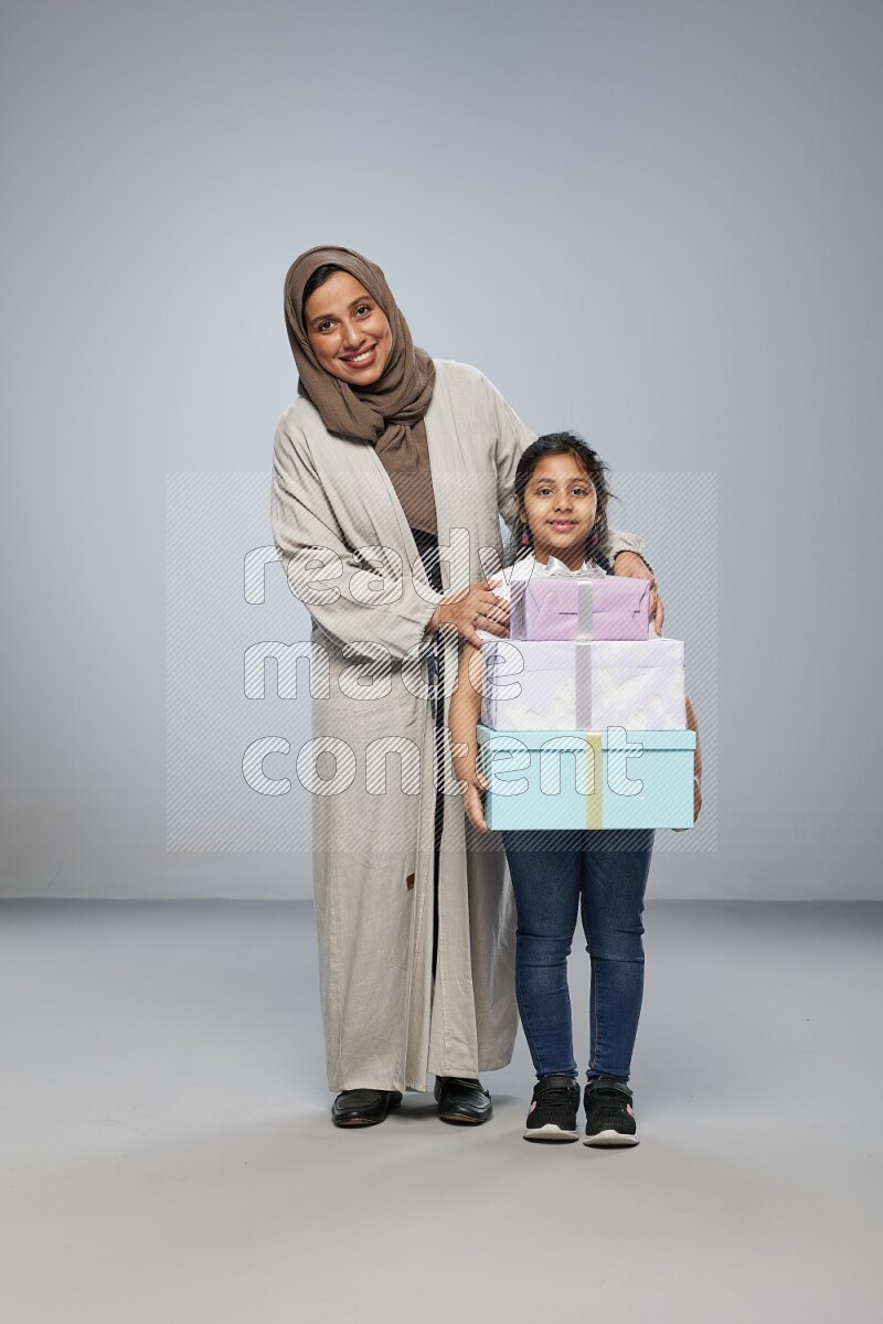 A girl giving a gift to her mother on gray background