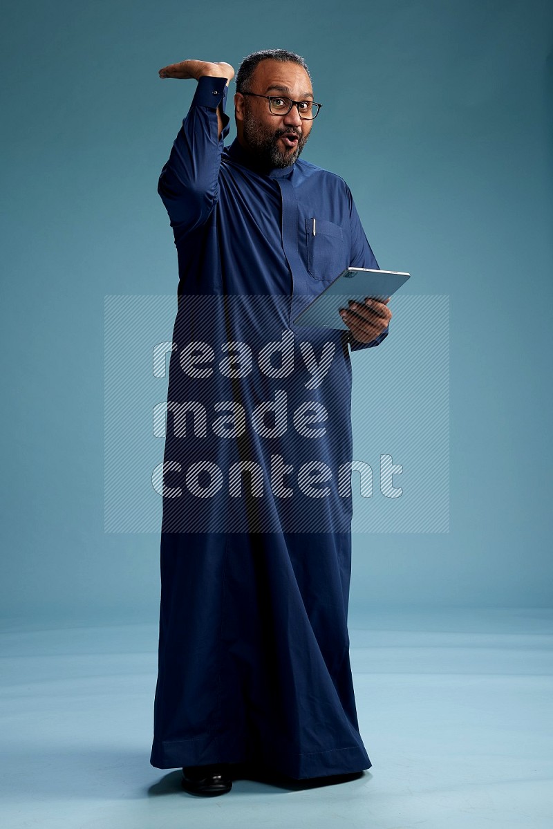 Saudi Man without shimag Standing working on tablet on blue background