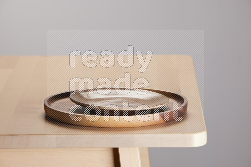 multi-colored pottery Plate placed on a light colored wooden tray on the edge of wooden table
