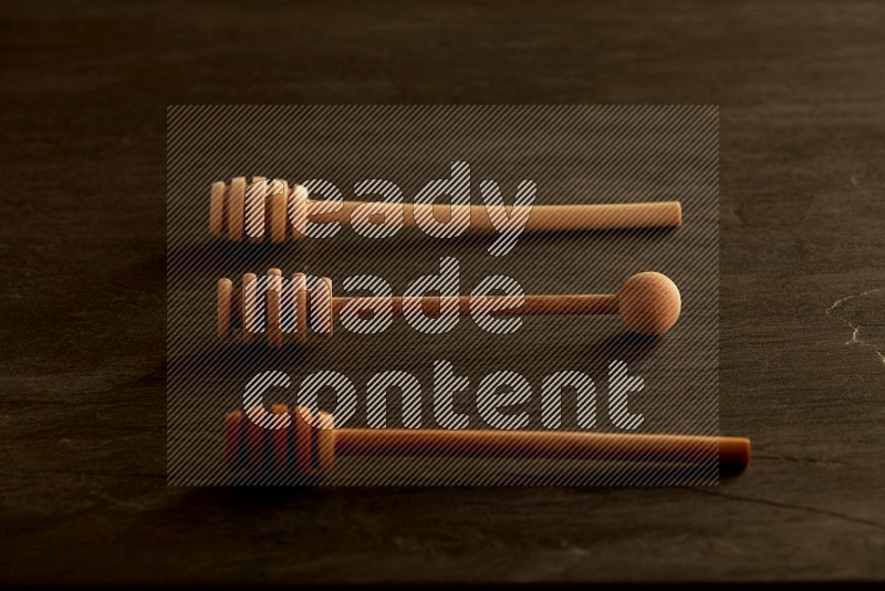 Wooden honey dipper on black slate background