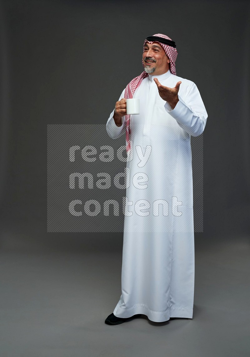 Saudi man with shomag Standing holding mug on gray background