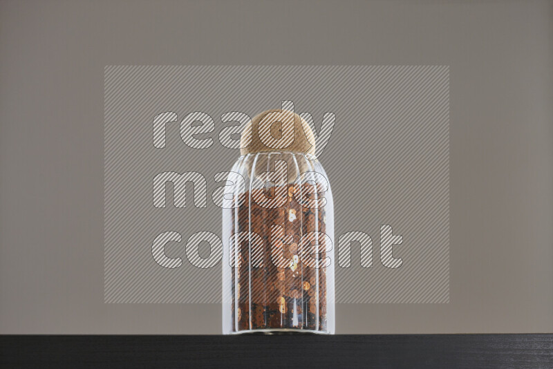 Sequins in a glass jar on black background