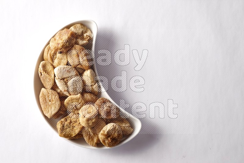 Dried figs in a crescent pottery plate on white background