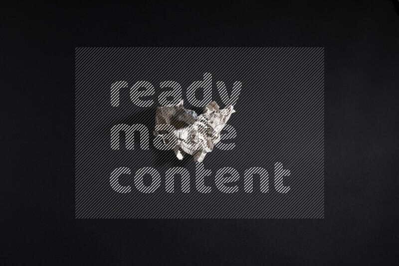 Crumpled newspaper sheet on black background