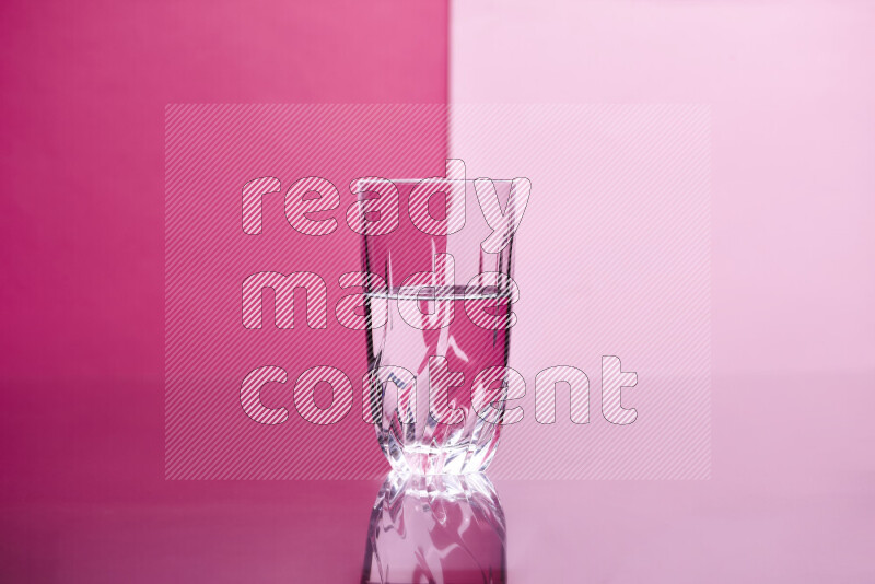 The image features a clear glassware filled with water, set against pink background