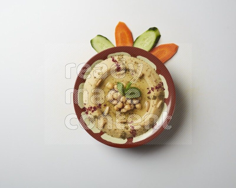 Hummus in a traditional plate garnished with zaatar & sumak on a white background