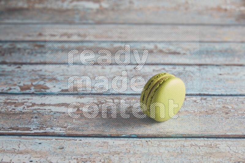 45º Shot of Green Pistachio macaron on light blue wooden background