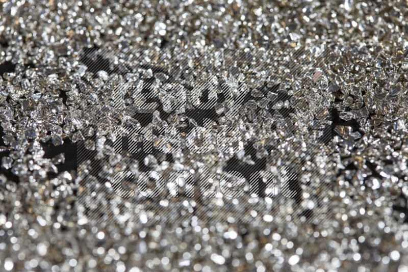 Silver shimmering fragments of glass scattered on a black background