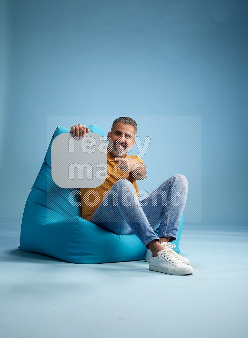 A man sitting on a blue beanbag and holding social media sign