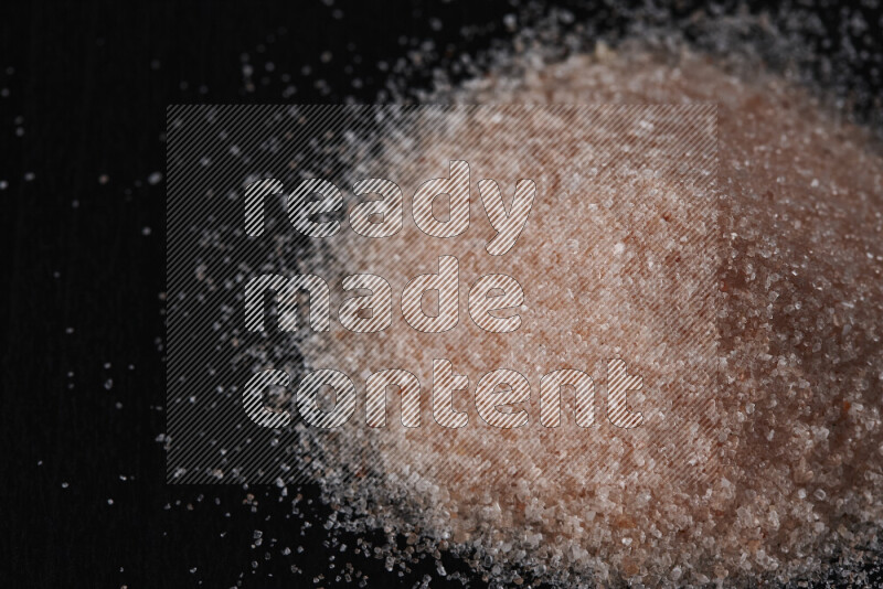 A bunch of fine himalayan pink salt on black background