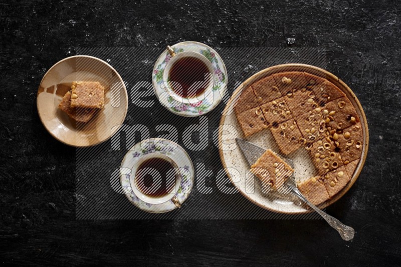 Basbousa with tea in a dark setup