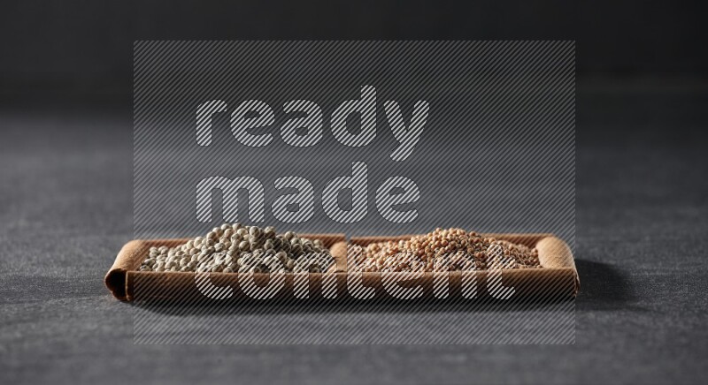 مربعان من أعواد القرفة ممتلئان بحبوب الخردل وحبوب الفلفل الأبيض علي خلفية سوداء