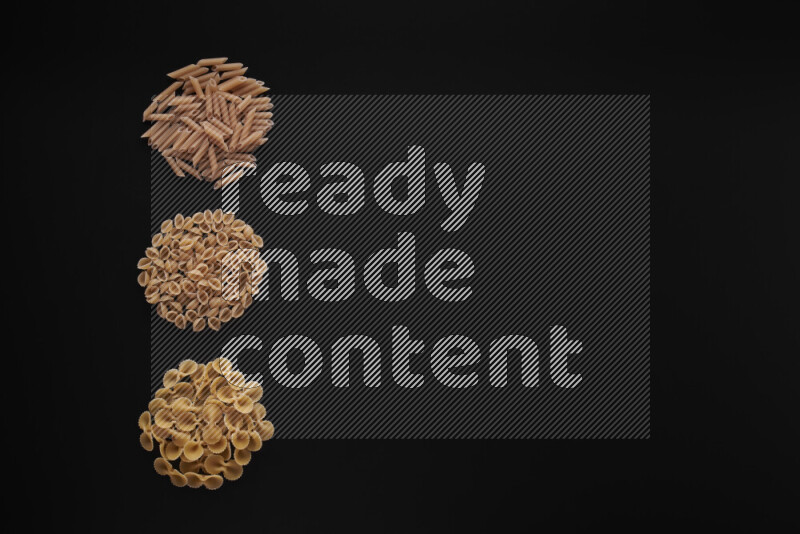 Different pasta types in 3 bunches on black background