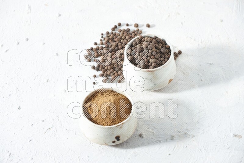 وعاءان بيج، أحدهما ممتلئ ببودرة بهار الفلفل الحلو والآخر بالحبوب مع البودرة والحبوب متناثرة على خلفية بيضاء