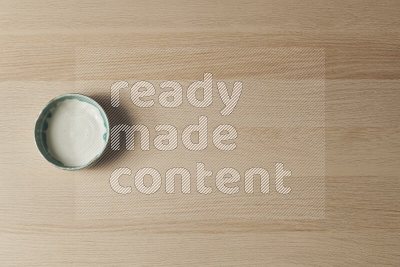 وعاء فخاري متعدد الألوان على خلفية خشبية فاتحة