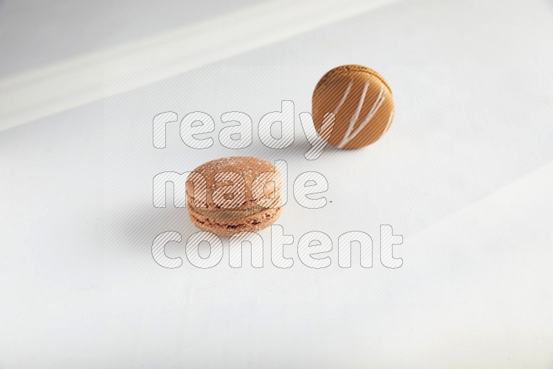 45º Shot of of two assorted Brown Irish Cream, and Brown Hazelnuts macarons on white background