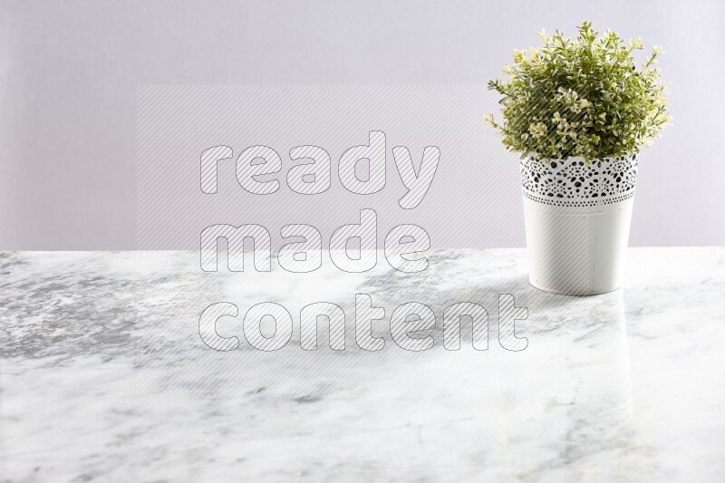 Artificial plant in white decorative pot on grey marble background
