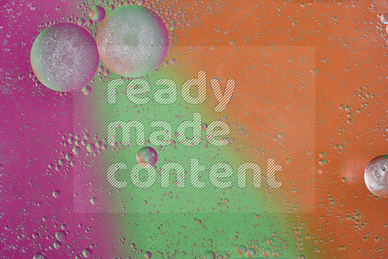 لقطات مقربة لفقاعات من الزيت على سطح الماء باللون البرتقالي والأخضر والوردي