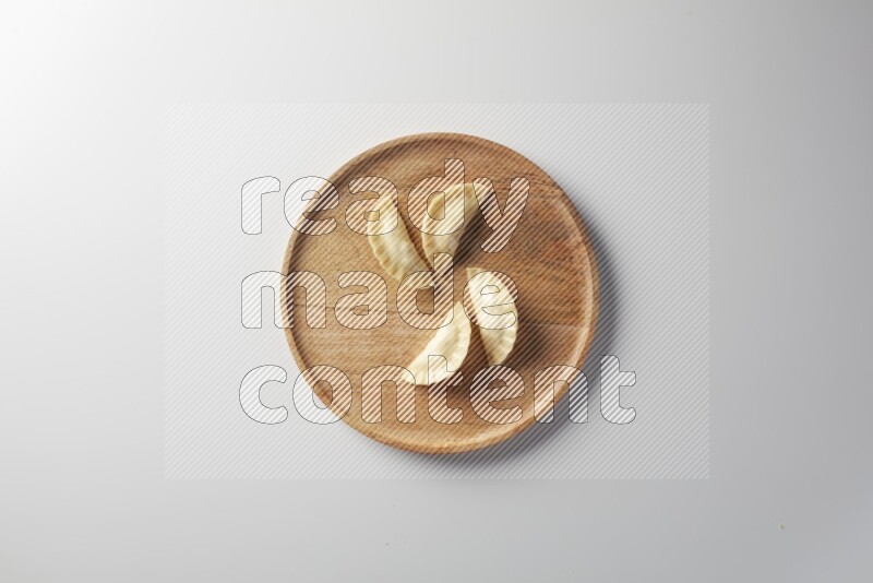 Four Sambosas on a wooden round plate on a white background