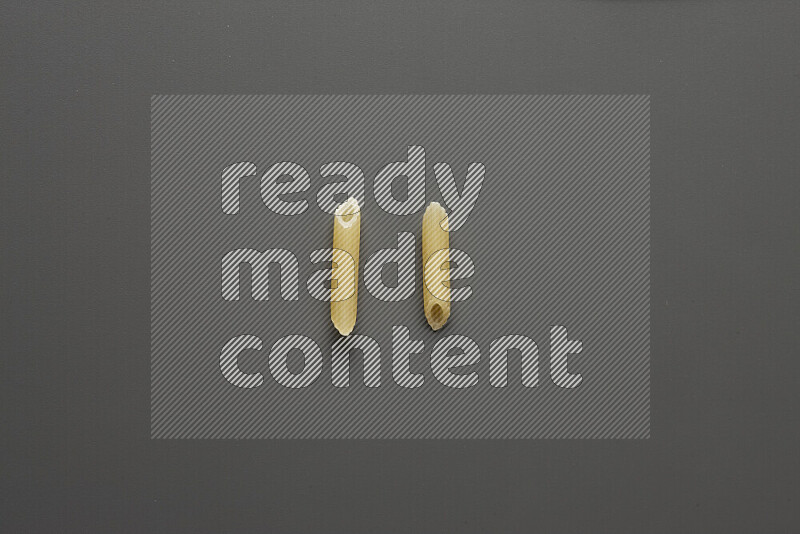 Mini penne pasta on grey background