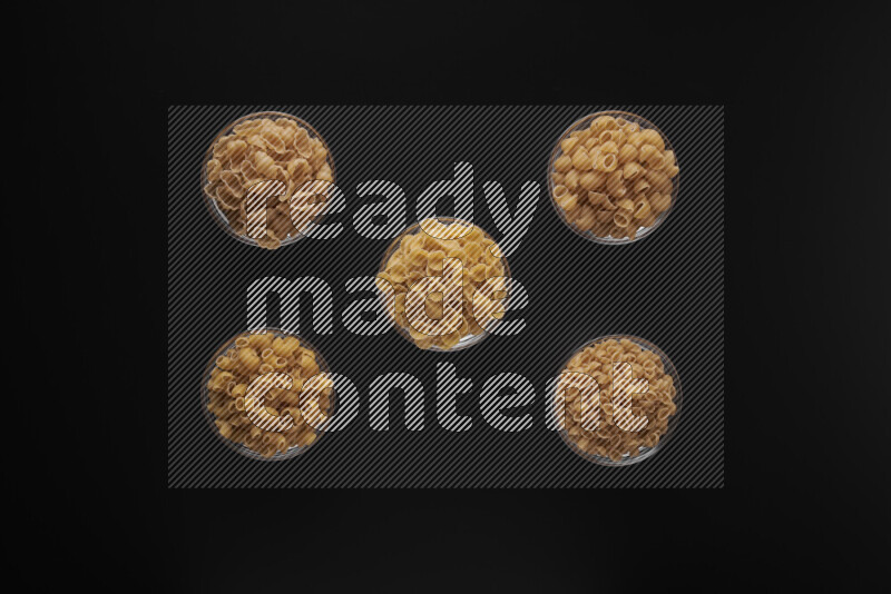 أنواع مختلفة من المعكرونة في أوعية زجاجية علي خلفية سوداء