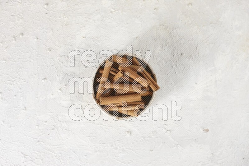 Cinnamon sticks in a ceramic bowl in different angles on white background