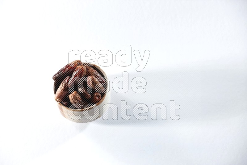A beige ceramic bowl full of dried dates on a white background in different angles