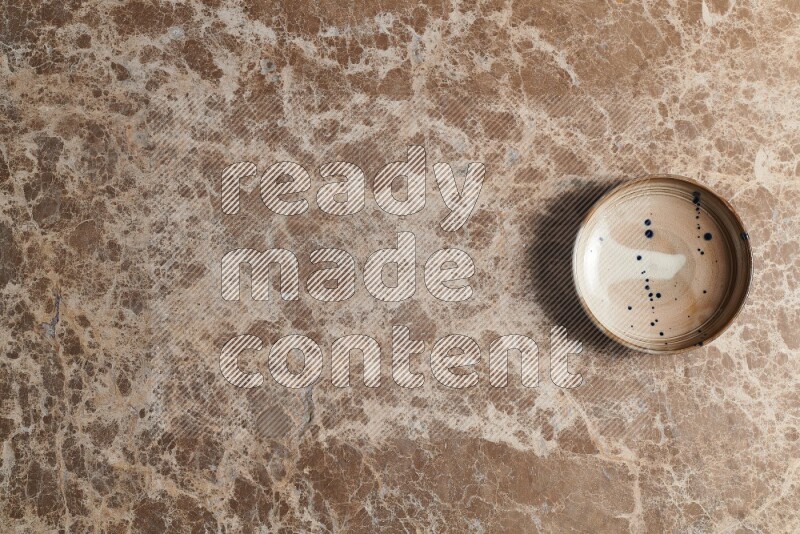 A multicolored pottery bowl on beige marble background