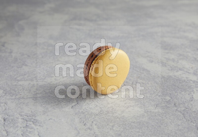 45º Shot of Yellow and Brown Chai Latte macaron on white  marble background